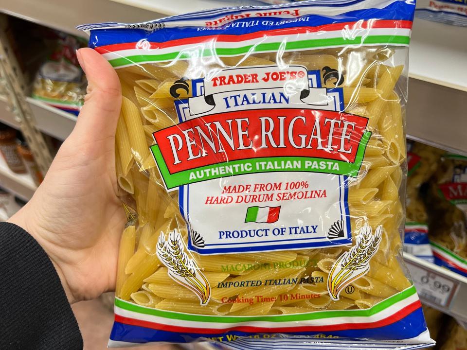 hand holding up a bag of penne pasta at trader joes