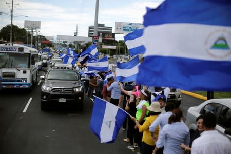 People hold Nicaraguan flags while forming a human chain to demand justice for people who died during anti-government protests, in Managua