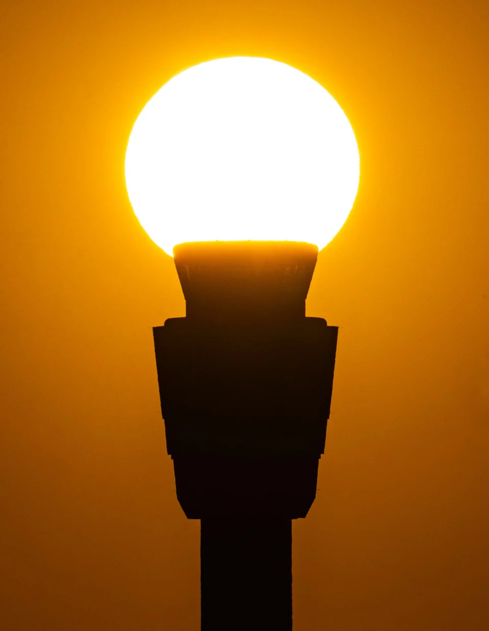 The sun silhouettes the air traffic control tower at Phoenix Sky Harbor International Airport in Phoenix on Sept. 6, 2023. An excessive heat watch for this weekend was issued by the National Weather Service.