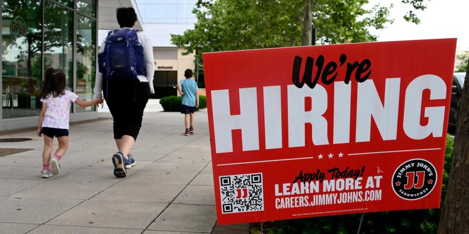 People walk past a "We're Hiring" sign at a Jimmy John's.