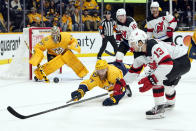 Nashville Predators defenseman Mattias Ekholm (14) pokes the puck away from New Jersey Devils center Nico Hischier (13) in the third period of an NHL hockey game Friday, Nov. 26, 2021, in Nashville, Tenn. (AP Photo/Mark Humphrey)