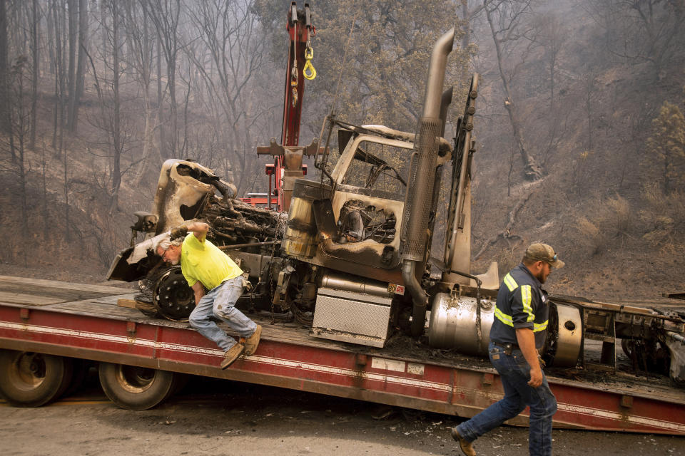 Bruce Palmer, left, and Justice Geib prepare to tow a truck scorched by the Delta Fire on Interstate 5 in the Shasta-Trinity National Forest, Calif., near Shasta Lake on Thursday, Sept. 6, 2018. The highway remains closed to traffic in both directions as crews battle the blaze. (AP Photo/Noah Berger)