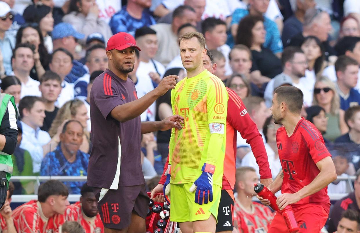 bayern munich's vincent kompany gestures with both hands as he chats to manuel neuer on the touchline at a football match