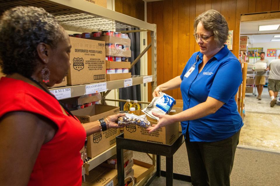 Volunteer Pam Rooks, left, and Anna Feldt, administrative support specialist for Catholic Charities of Northeast Kansas, pack a box of food items specific to The Emergency Food Assistance Program on Thursday.