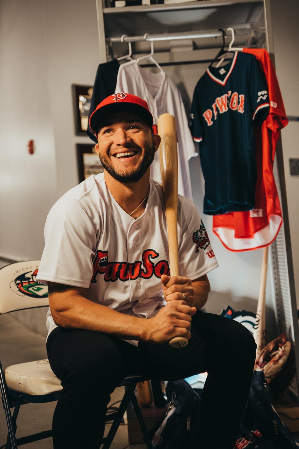 Yolmer Sanchez dons a PawSox jersey and cap, while sitting on a McCoy Stadium chair.