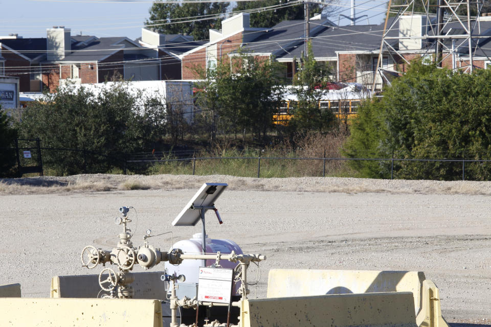 A natural gas well is juxtaposed with apartment buildings a few hundred feet away in Arlington, Texas, on Monday, Oct. 25, 2021. The site, known as "AC-360," is operated by TEP Barnett, a subsidiary of French energy giant Total Energies. It is one of Total's 33 well sites in Arlington that contain 163 wells. The company has proposed adding three new wells at this site. Some residents of the predominately Hispanic and Black neighborhood, as well as parents and staff at a daycare near the site, oppose the plan, citing health concerns. (AP Photo/Martha Irvine)