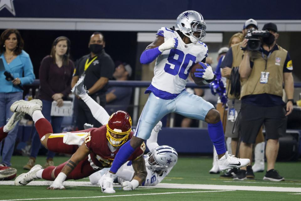 Dallas Cowboys defensive end Demarcus Lawrence (90) breaks tackles on the way to the end zone for a touchdown after intercepting a pass throw by Washington Football Team's Taylor Heinicke (4) in the first half of an NFL football game in Arlington, Texas, Sunday, Dec. 26, 2021. (AP Photo/Ron Jenkins)