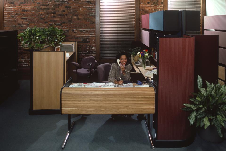 In a modular office, an unidentified woman sits at a desk and talks on the telephone (April, 1984). The photo was taken as part of a shoot for the Herman Miller Furniture brochure. (Photo by Susan Wood/Getty Images)