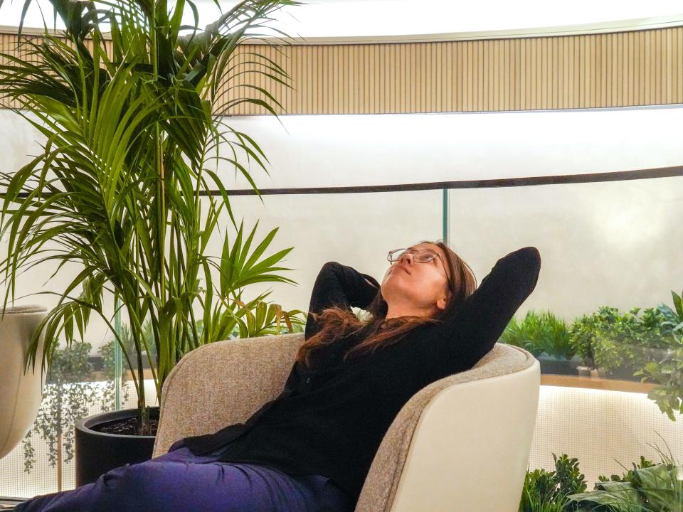 The author leans back in a white love seat with plants all around