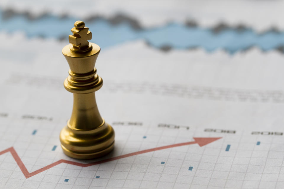 A king chess piece on a piece of paper displaying a chart line and data points.