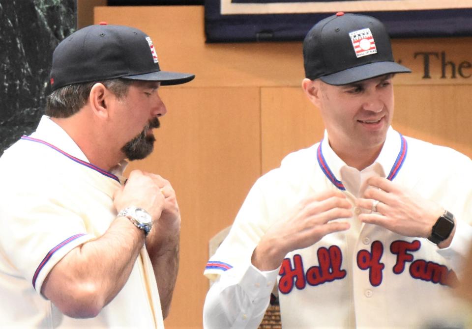 New inductees Todd Helton and Joe Mauer (from left) put on their Hall of Fame jerseys in the baseball museum's plaque gallery at a news conference Jan. 25 in Cooperstown, New York.