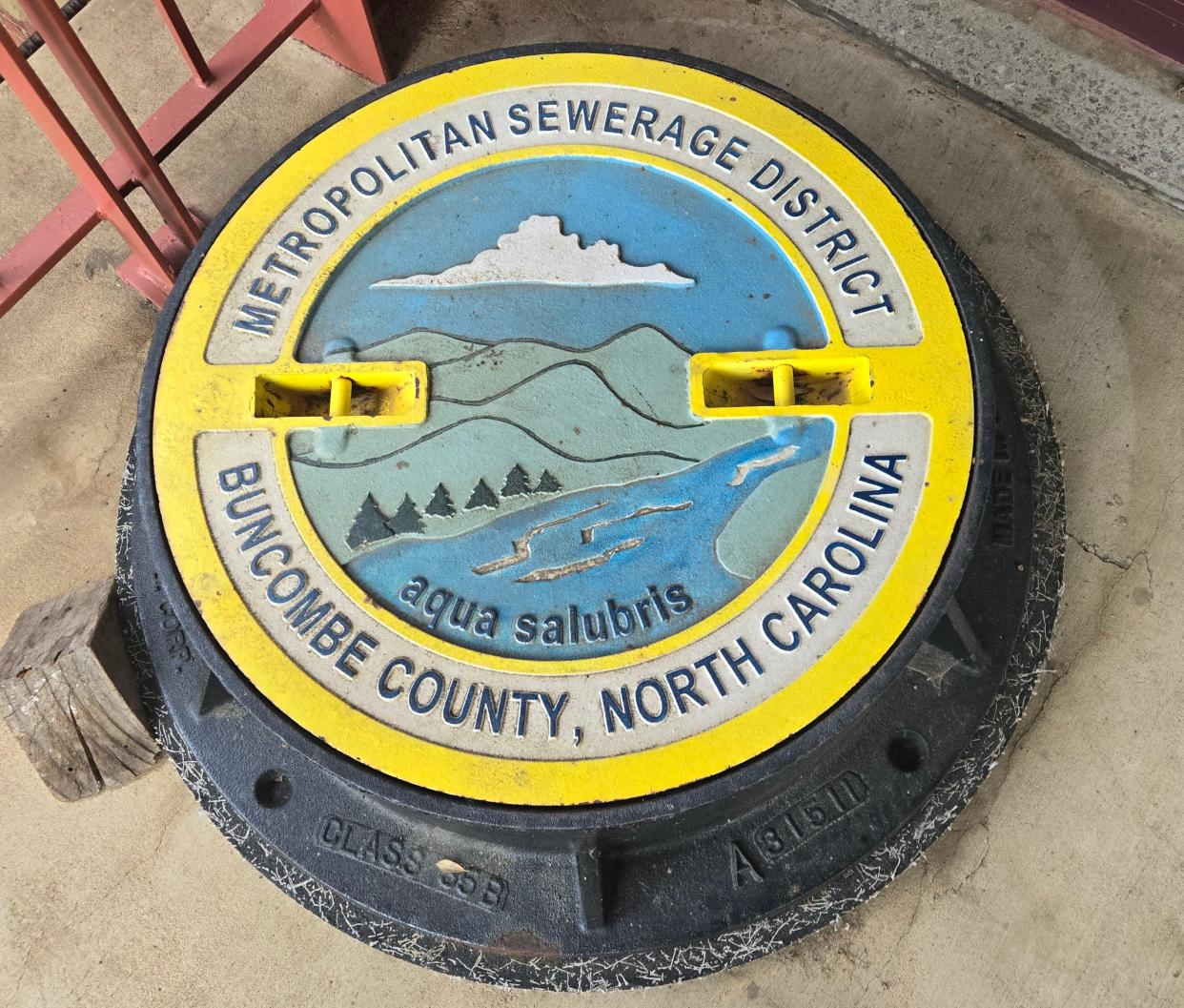 A painted version of the Metropolitan Sewerage District of Buncombe County's logo-designed manhole cover that is for display only.