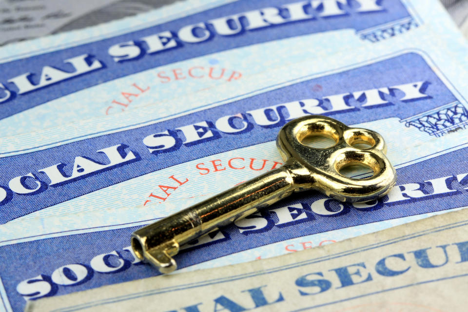 Three Social Security cards with a brass key on top of them.