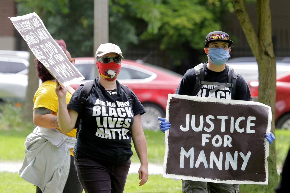 A protester holds a sign that reads "Justice for Manny" in this June 5, 2020 file photo in Tacoma, Wash., during a protest against police brutality. On Thursday, May 27, the Washington state attorney general filed criminal charges against three police officers in the death of Manuel Ellis, a Black man who died after telling the Tacoma officers who were restraining him he couldn't breathe.