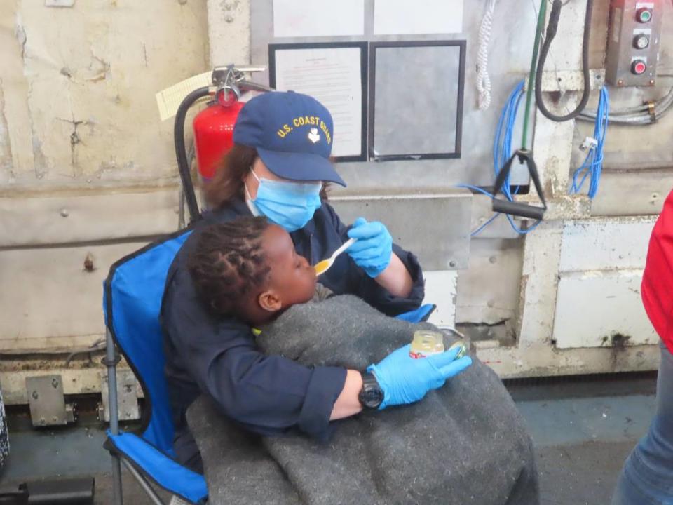 A U.S. Coast Guard crew member feeds a young child who was rescued from a distressed migrant vessel off Key Largo Monday, Nov. 21, 2022.