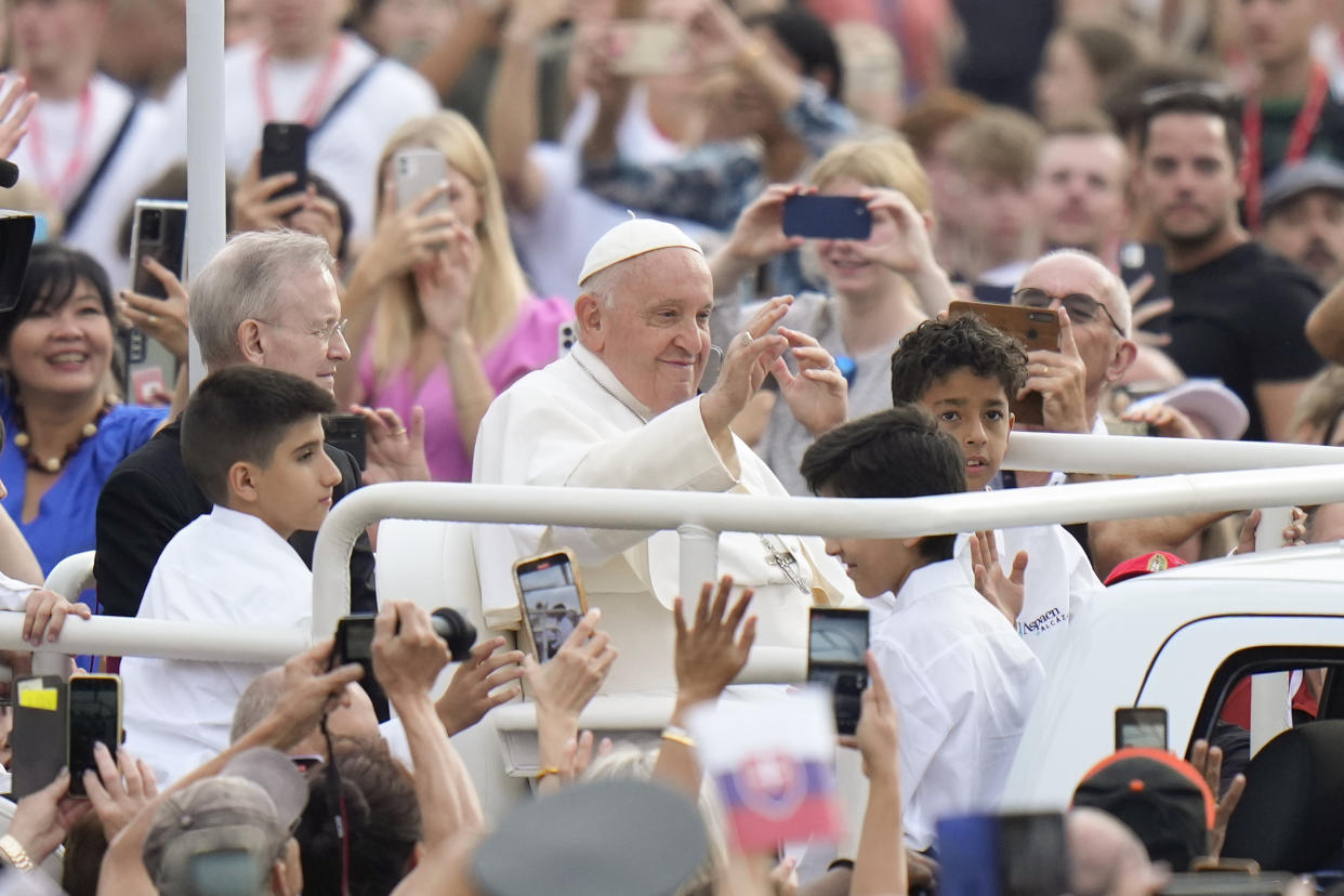 Pope Francis among a crowd of people, many of whom hold cellphones out.