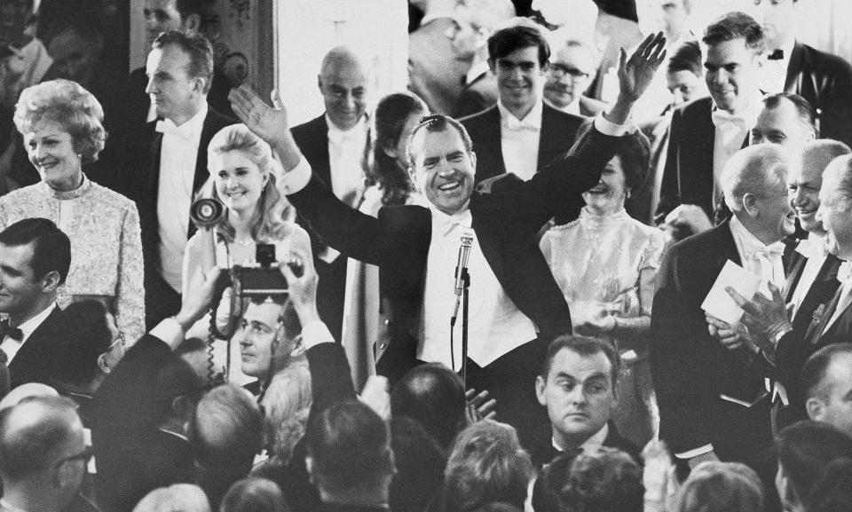 Pres. Richard Nixon, center, greets the crowd at the Mayflower Hotel Inaugural Ball, Jan. 21, 1969, Washington, D.C. From left are Pat Nixon, daughter Tricia Nixon, Julie (hidden) and David Eisenhower. (AP Photo/Gary Settle)