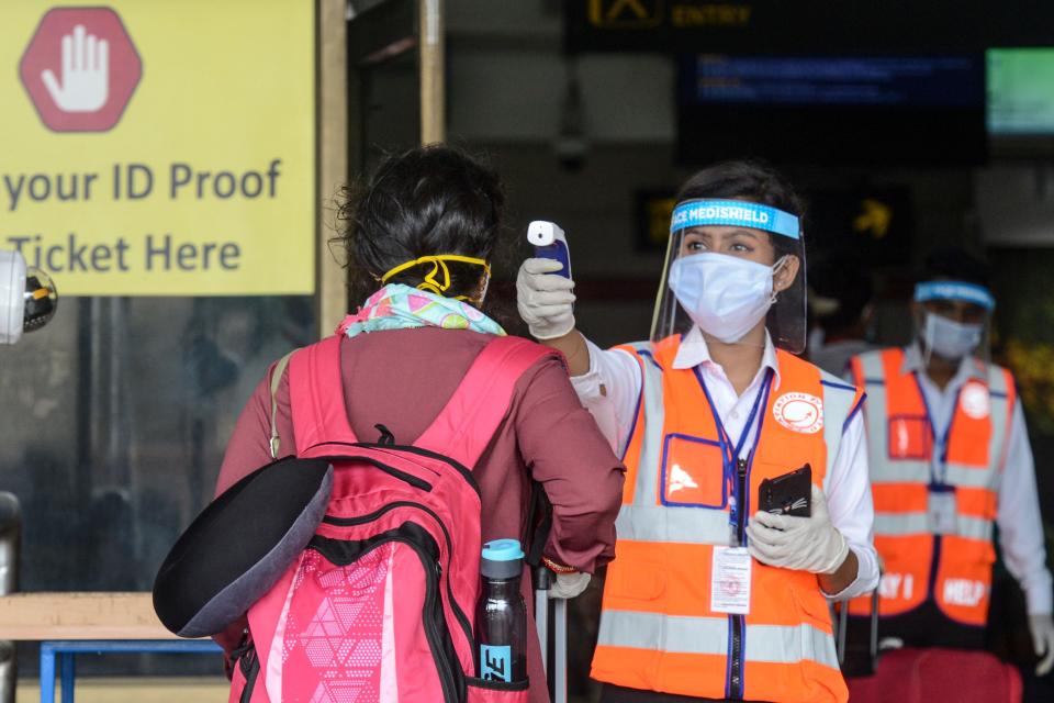 File: An airport employee wearing a face shield checks the body temperature of a passenger at Bagdogra airport, on the outskirts of Siliguri on May 28, 2020 (AFP via Getty Images)
