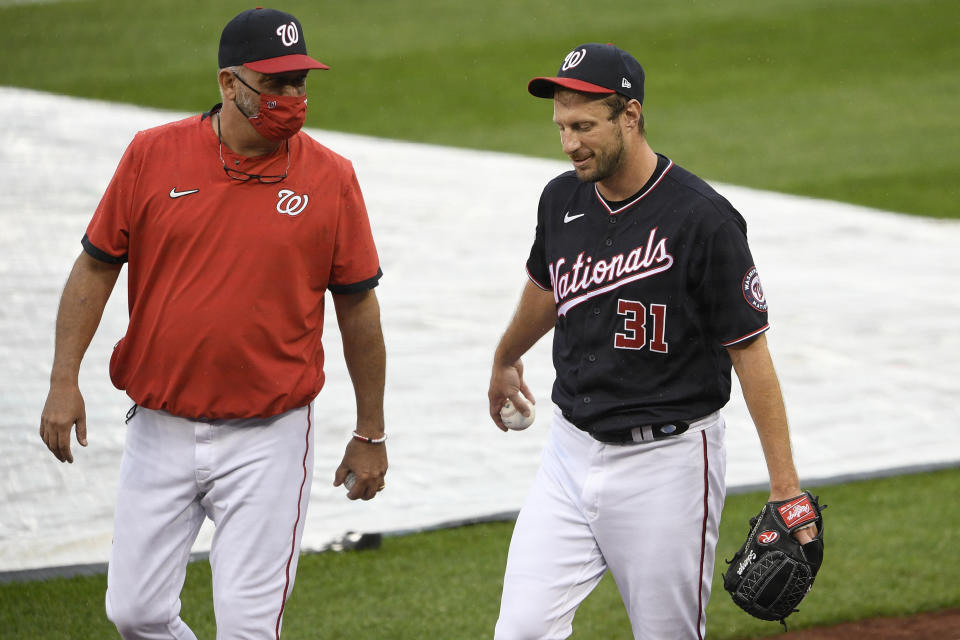 Washington Nationals starting pitcher Max Scherzer (31) walks on the field next to pitching coach Paul Menhart, left, before a baseball game against the New York Mets, Friday, Sept. 25, 2020, in Washington. The game was postponed due to inclement weather. (AP Photo/Nick Wass)