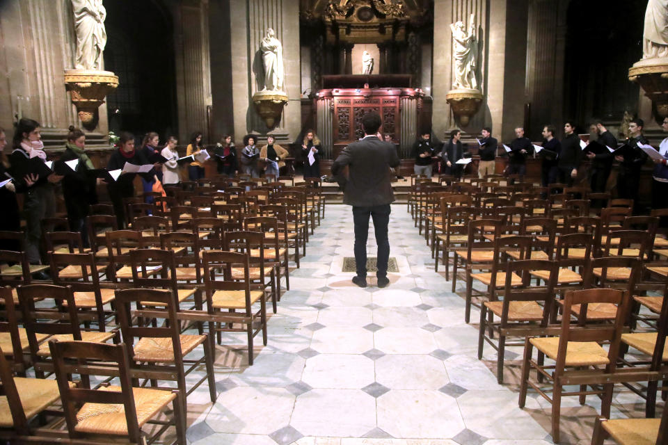 In this photo taken Monday, Dec. 16, 2019, Notre Dame cathedral choir's director Henri Chalet directs the Notre Dame choir during a rehearsal at the Saint Sulpice church in Paris. Notre Dame Cathedral kept holding services during two world wars as a beacon of hope amid bloodshed and fear. It took a fire in peacetime to finally stop Notre Dame from celebrating Christmas Mass for the first time in more than two centuries. (AP Photo/Michel Euler)