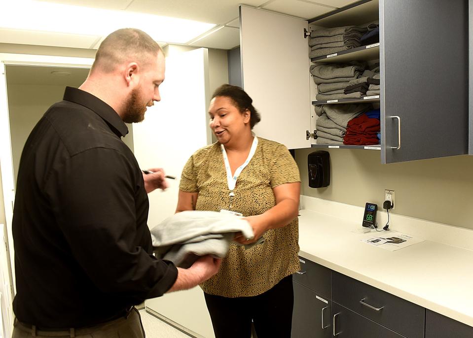 Jessica Trice, a Burrell behavioral specialist, gives clean clothing to Brandon Bennett, care coordinator, during a client intake training exercise on Thursday at the Burrell rapid access unit at 1805 E. Walnut St.