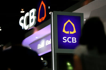 People walk pass the logos of Siam Commercial Bank at an exhibition hall in Bangkok, Thailand, May 12, 2016. REUTERS/Athit Perawongmetha/File Photo