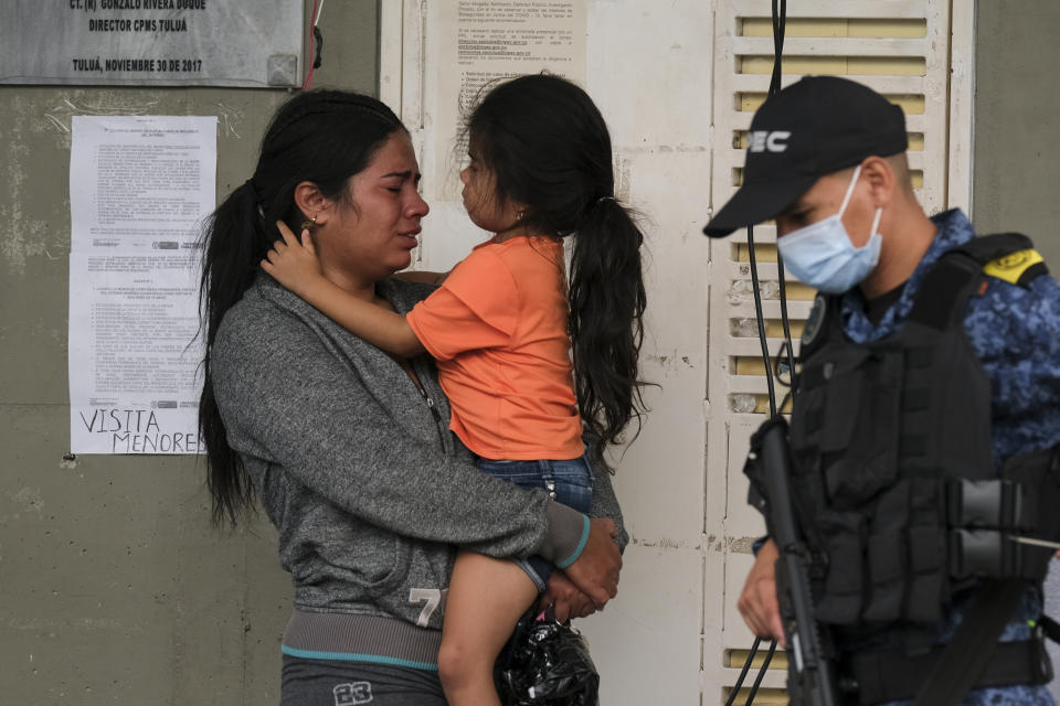 A woman and child wait outside a jail for inmate status after a deadly fire at the prison in Tulua, Colombia, Tuesday, June 28, 2022. Authorities say at least 49 people were killed after the fire broke out during what appeared to be an attempted riot early Tuesday. (AP Photo/Juan Jose Horta)