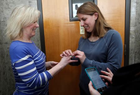 Elizabeth Gardiner (L) and Stephanie Citron exchange rings during their wedding ceremony in the hallway of the Oakland County Courthouse as the woman officiating the wedding reads the marriage vows from her cell phone, after a Michigan federal judge ruled a ban on same-sex marriage violates the U.S. Constitution and must be overturned in Pontiac, Michigan March 22, 2014. REUTERS/Rebecca Cook