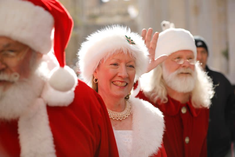 People dressed in Santa Claus outfits, part of a group of Santa Clauses from around the world, greet passers-by as they tour Jerusalem's Old City