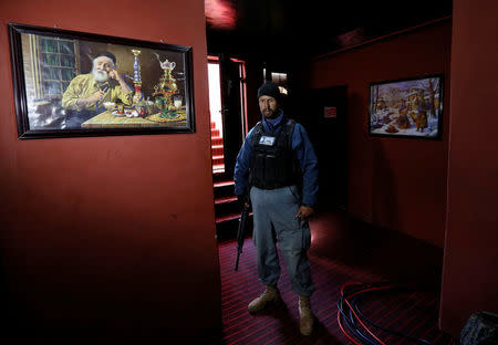 A policeman stands next to an image showing a water pipe during a raid confiscating shisha water pipes in Kabul, Afghanistan November 27, 2016. REUTERS/Mohammad Ismail