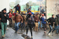 Anti-government protester run during clashes with security forces in Baghdad, Iraq, Saturday, Jan. 25, 2020. Security forces set fire to anti-government protest tents in the country's south early Saturday and re-opened key public squares in Baghdad that had been occupied by demonstrators for months. (AP Photo/Hadi Mizban)