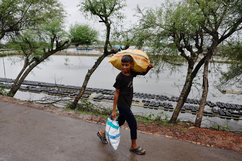 A boy carries his belongings as he moves to a cyclone shelter before the Cyclone Remal hits the country in the Shyamnagar area of Satkhira