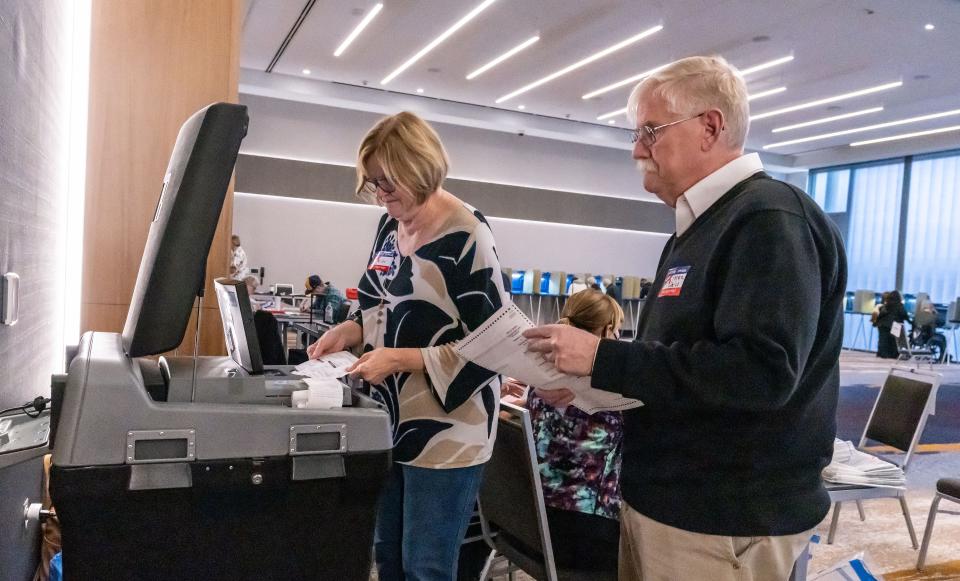 Poll workers Jan Story and Peter Geiss feed absentee ballots into a voting machine at the Brookfield Conference Center on Tuesday, November 8, 2022.