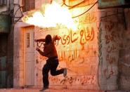 A masked Palestinian protester throws a petrol bomb at Israeli soldiers in the West Bank town of Hebron on December 11, 2017