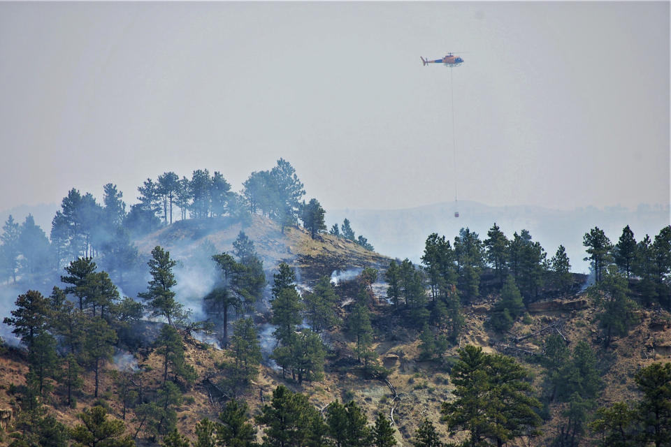 In this photo provided by the Bureau of Land Management, a helicopter works above the Devil's Creek Fire in central Montana on Thursday, July 22, 2021. Five firefighters were injured when a thunderstorm and swirling winds in central Montana blew a lightning-caused wildfire back on them, federal officials said Friday, July 23, 2021. (Mark Jacobsen/Bureau of Land Management via AP)