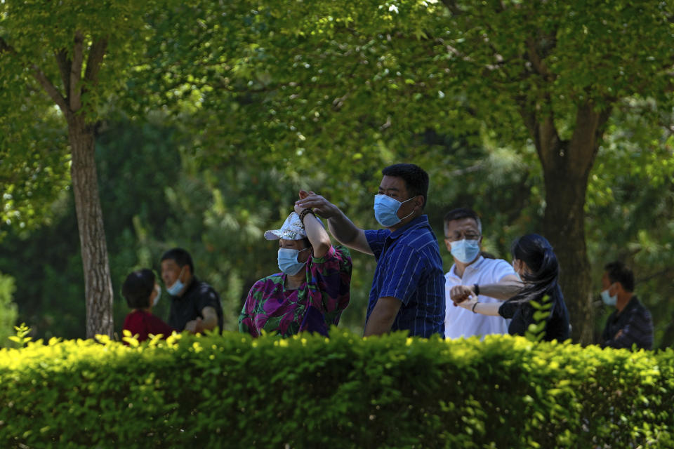 Resident wearing face masks enjoy a social dance outside the shuttered Chaoyang Park due to pandemic measures by authorities on Sunday, May 15, 2022, in Beijing. (AP Photo/Andy Wong)