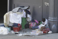 A homeless person sits on the street in San Francisco, Thursday, April 2, 2020. Since the beginning of an international pandemic, officials in California have said one population is particularly vulnerable to contracting the coronavirus and spreading it to others: the homeless. (AP Photo/Jeff Chiu)