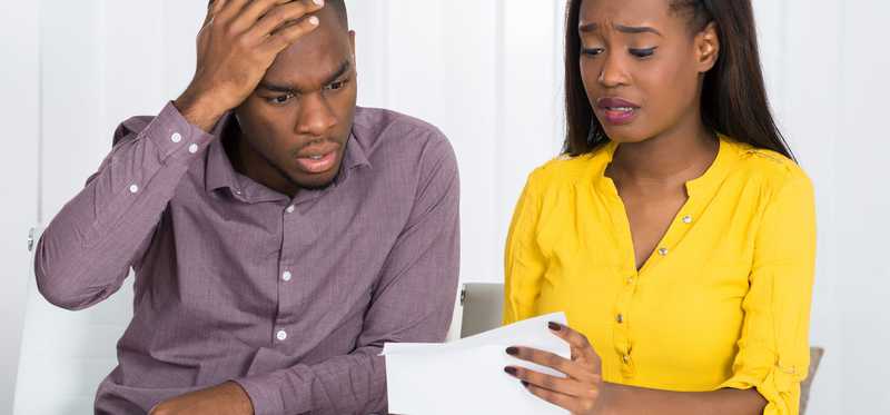 Young couple looks upset by mail they are reading.