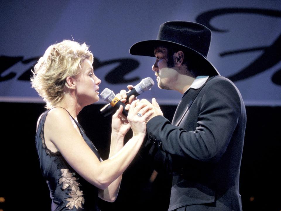 Faith Hill in a black dress with lace detail and Tim McGraw in a black suit and cowboy hat