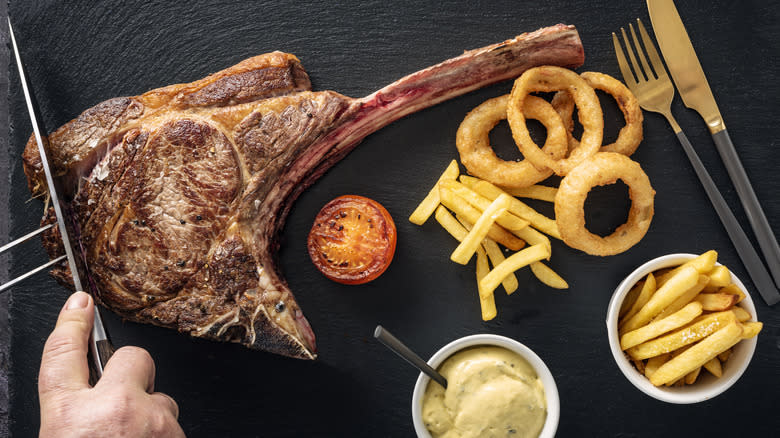 top wiew of tomahawk with onion rings and fries