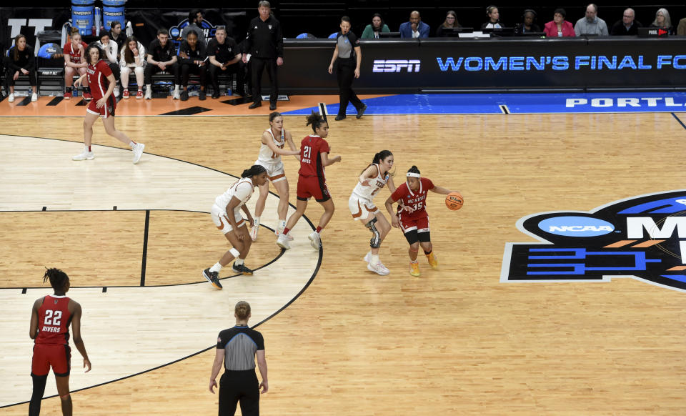 North Carolina State guard Zoe Brooks, right, dribbles the ball against Texas guard Shaylee Gonzales, second from right, at the top of the three-point line during the second half of a Elite Eight college basketball game in the NCAA Tournament, Sunday, March 31, 2024, in Portland, Ore. (AP Photo/Steve Dykes)