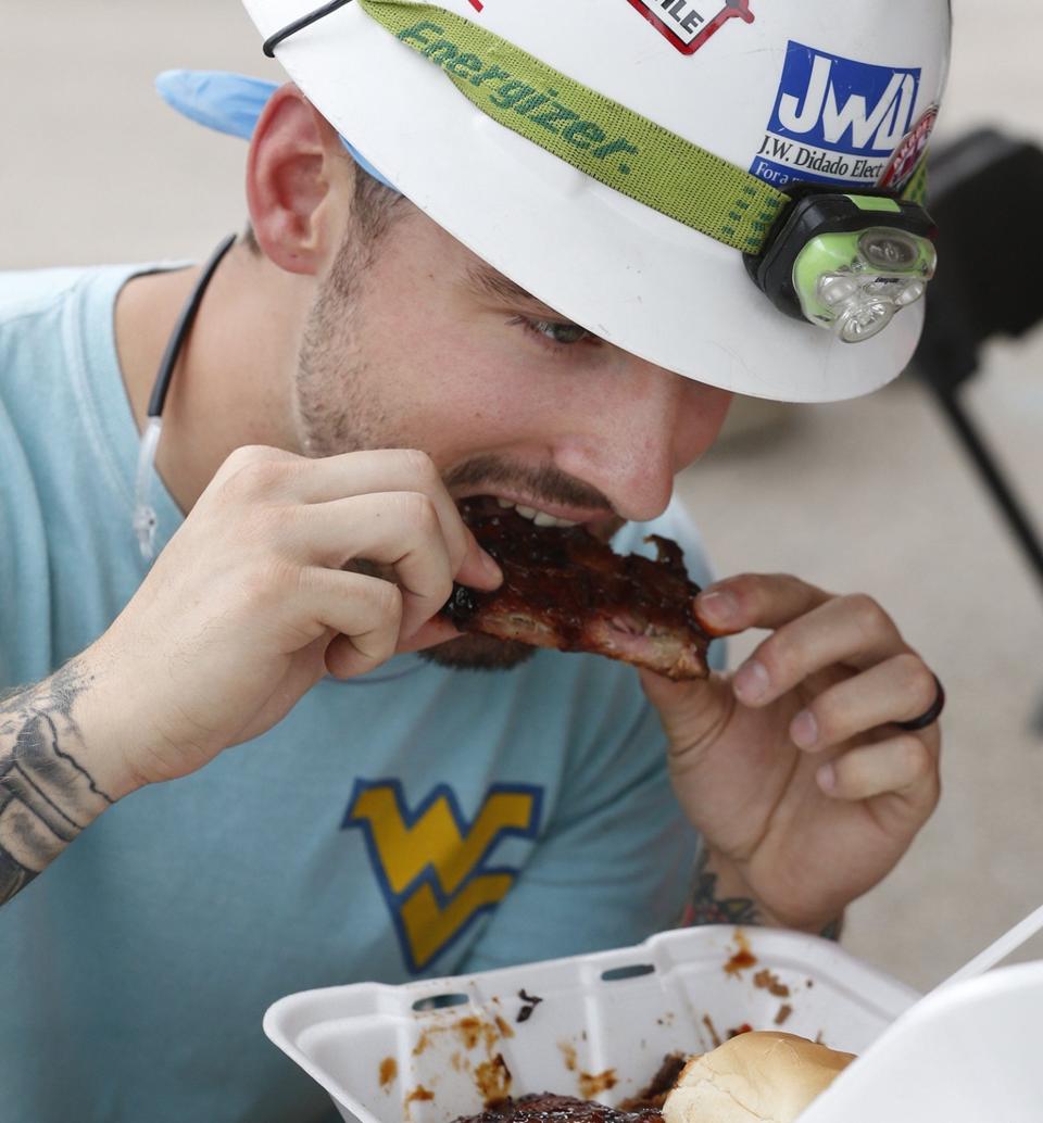 Shay Sharp enjoys eating ribs during his lunch break during the 2019 Rib, White and Blue Akron's National Rib Festival.