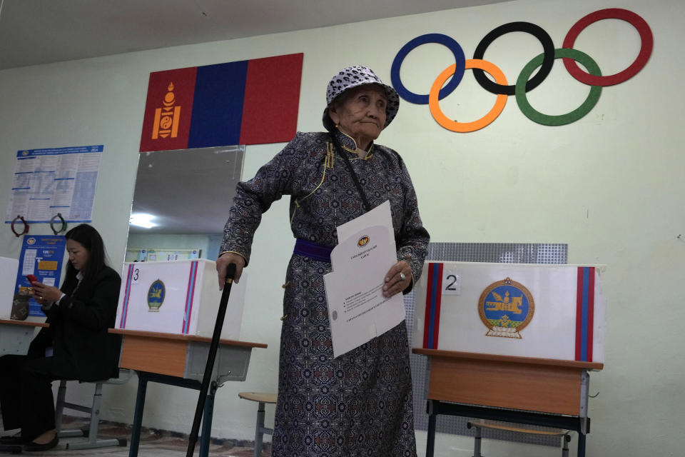 An elderly Mongolian woman prepares to feed her vote into counting machines at a polling station in Ulaanbaatar, Mongolia, Friday, June 28, 2024. Voters in Mongolia are electing a new parliament on Friday in their landlocked democracy that is squeezed between China and Russia, two much larger authoritarian states (AP Photo/Ng Han Guan)