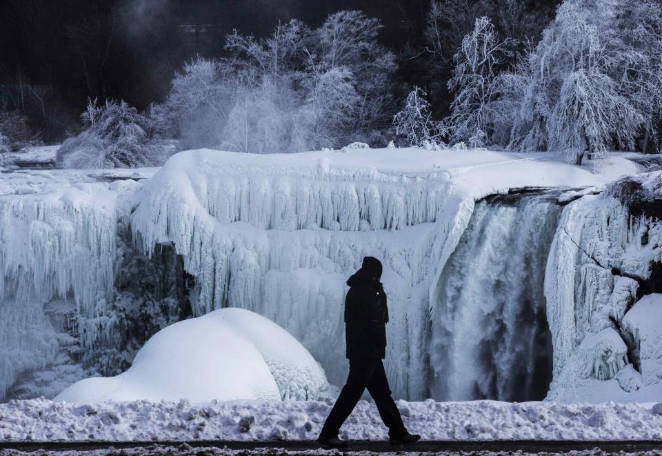 A man walks in front of the partially frozen American side of the Niagara Falls on during sub-freezing temperatures in Niagara Falls, Ontario March 3, 2014. REUTERS/Mark Blinch