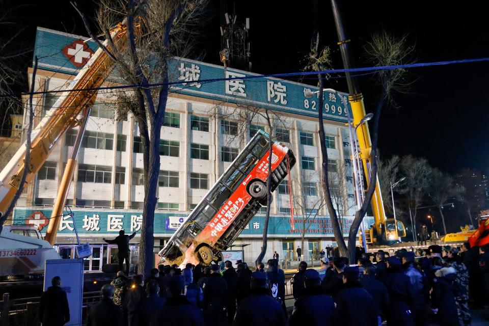 This photo taken on January 13, 2020 shows Chinese rescuers watching as a bus is lifted out after a road collapse in Xining in China's northwestern Qinghai province. - An enormous sinkhole swallowed passers-by and a public bus in northwest China, reported state media on January 14, injuring fifteen people while another ten are still missing. (Photo by STR / AFP) / China OUT (Photo by STR/AFP via Getty Images)
