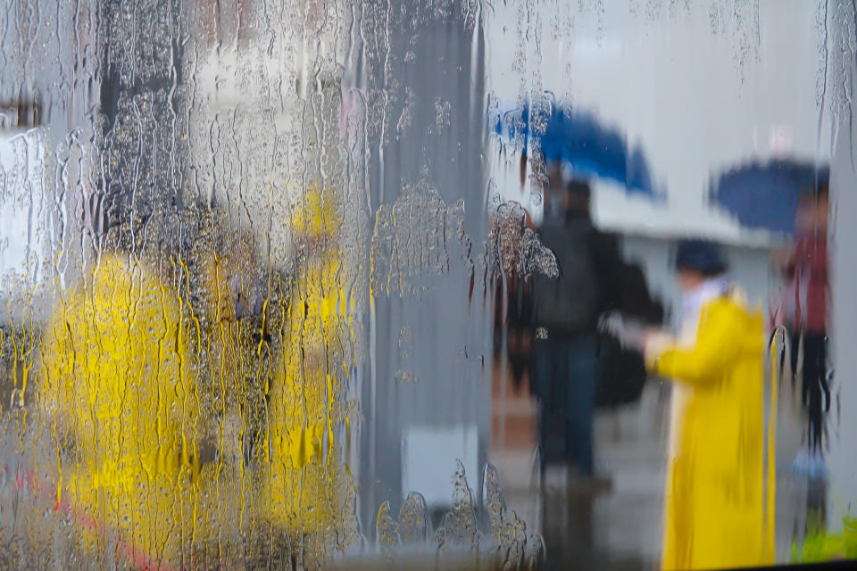 View from a vehicle window of people in yellow rain gear and with blue umbrellas in Nova Scotia, Canada. (Photo from Getty Images)