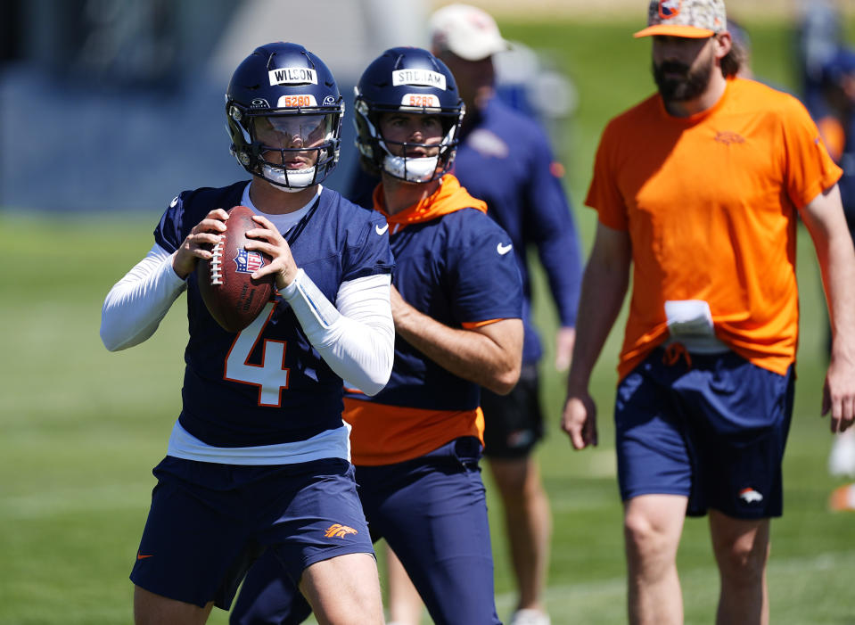 Denver Broncos quarterbacks Zach Wilson, front, and Jarrett Stidham take part in drills as quarterbacks coach Davis Webb, back, looks on during practice at the NFL football team's training headquarters Thursday, May 23, 2024, in Centennial, Colo. (AP Photo/David Zalubowski)