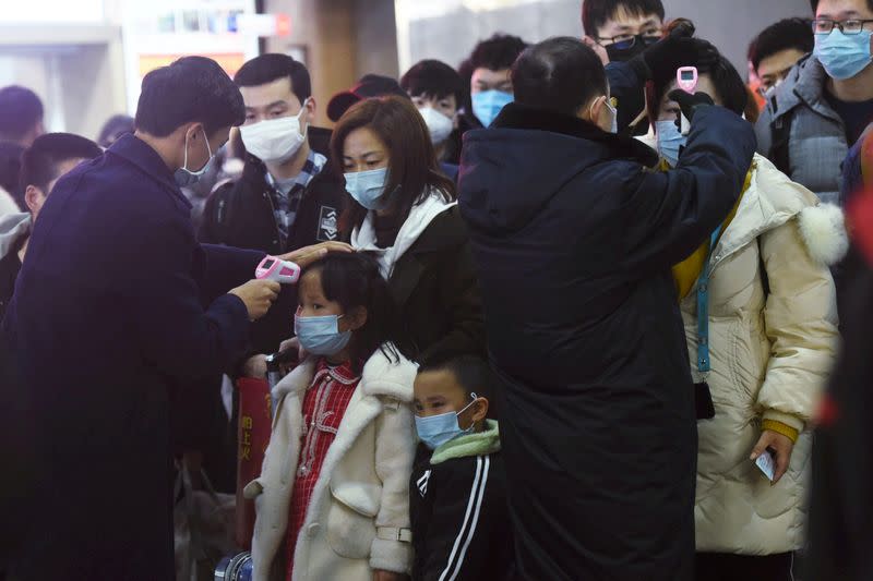 Personal verifica la temperatura corporal de los pasajeros que llegan del tren de Wuhan a Hangzhou, en la estación de tren de Hangzhou, antes del Año Nuevo Lunar chino.