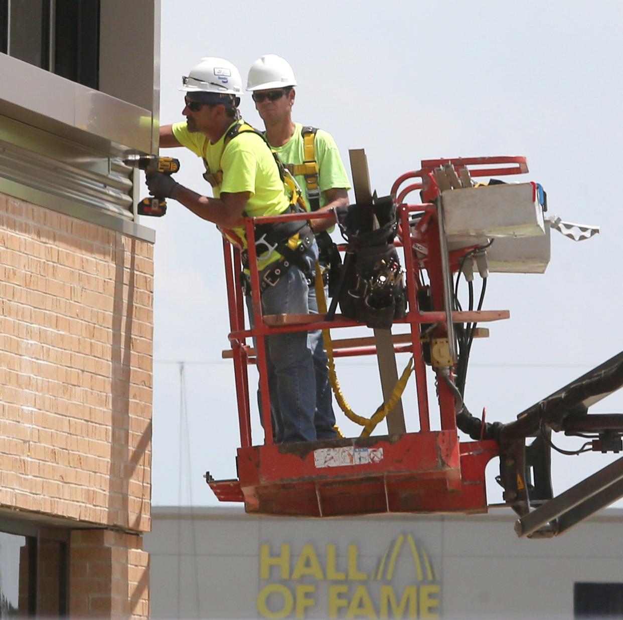 Construction workers work on the Constellation Center for Excellence at the Hall of Fame Village in Canton in 2021.