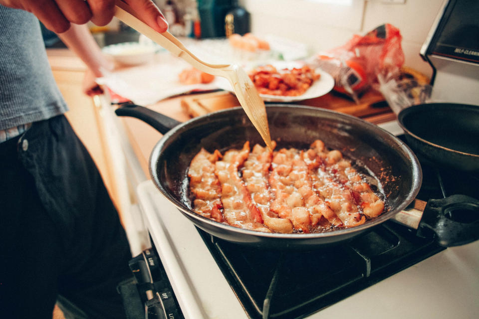 Man Frying Bacon in Frying Pan on Stove, Unhealthy Diet, Breakfast Food, Paleo Diet, Greasy Bacon, Greasy Food. Conceptual image for overeating and dieting.